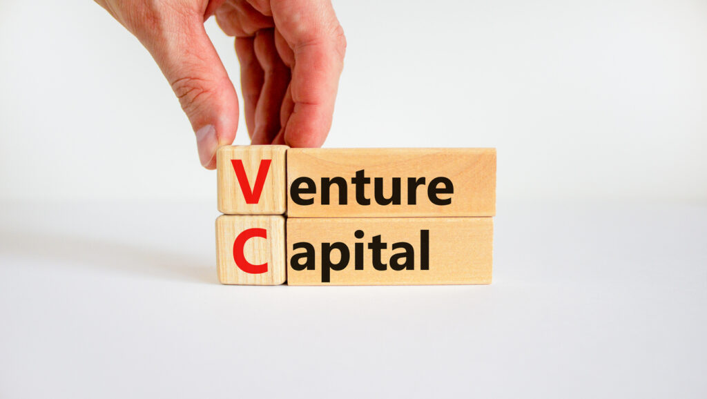 VC venture capital abbraviation symbol. Concept words 'VC venture capital' on wooden blocks on white table, white background, copy space. Businessman hand. Business and VC venture capital concept.
