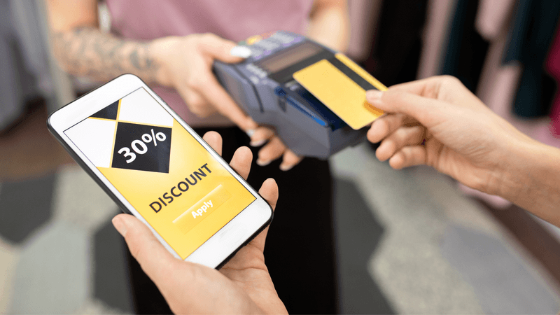  a person paying by card and holding a phone in another hand with 30% discount offer