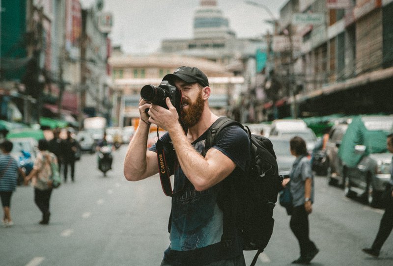 a man on a busy street taking a photo. photography business can be a rewarding business