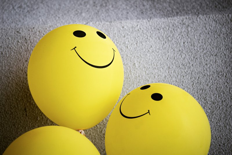 yellow balloons with smiley faces on the grey background. to improve your customer service skills, you need to use positive language